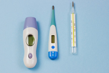 Infrared thermometers, electronic and mercury on a blue background.