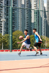 Fototapeta premium young asian adult men playing basketball on outdoor court