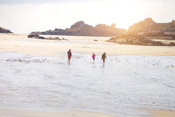 Obraz premium Dad and two daughters running along the beach