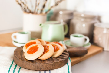 Still life with homemade cookies with jam and fresh coffee on the table near with flowers. Breakfast in the interior of the kitchen at home. Lifestyle, vintage photo.