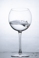 Water splashing in the luxury wine glass close up. Concept of good healthy and refreshment.