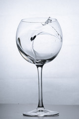 Water splashing in the luxury wine glass close up. Concept of good healthy and refreshment.
