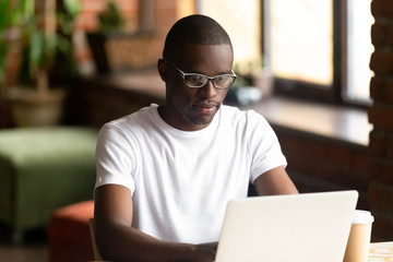 Focused black millennial guy working on computer