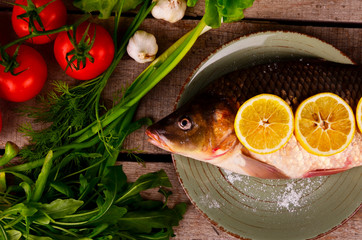 Delicious fresh fish on dark vintage background. Fish with aromatic herbs, spices and vegetables - healthy food, diet or cooking concept