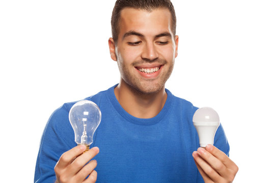 portrait of young man, holding LED bulb and old fachion bulb on white background