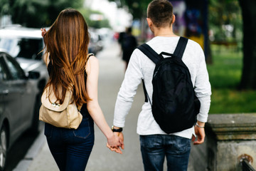 Obraz premium portrait of two students carrying bags walking and talking in a park