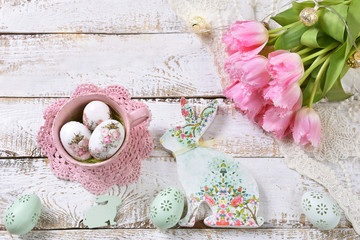 easter flat lay with bunch of pink tulips eggs and bunny