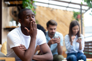 Diverse friends sitting in cafe focus on bored black guy