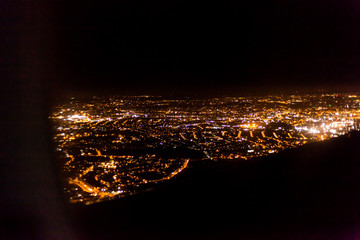 Dark background view of city with lights from aeroplane. Night lights in the city. Aeroplane view of dark nigh above the city lights