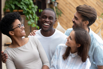 Black and caucasian mates embracing laughing posing for photo