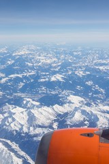 Aerial view of snow covered mountains - snowy mountain peaks - high mountains - Alps out of a Airplane window 