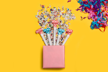 Caja con confeti cumpleaños sobre fondo amarillo brillante. Vista superior. Concepto: festejo