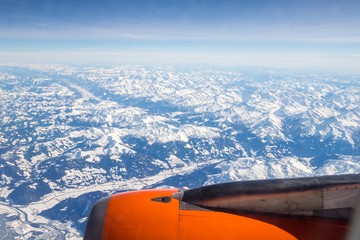 Aerial view of snow covered mountains - snowy mountain peaks - high mountains - Alps out of a Airplane window 