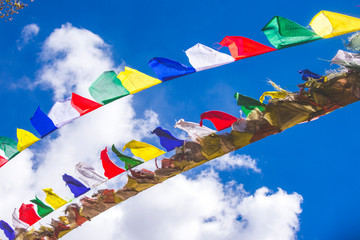 Multicolored Buddhist flags on a blue sky