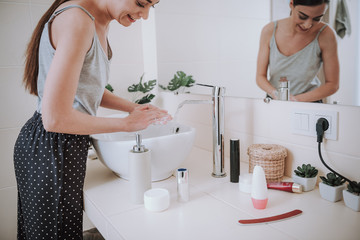 Close up of a soap bottle in the kitchen being used by a pleasant woman