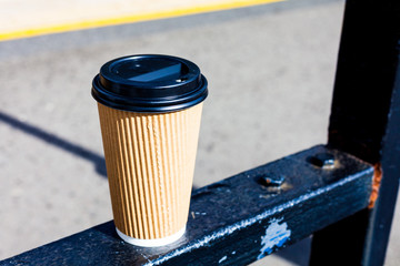 Espresso coffee for takeaway standing on the metal gate. Sunny day with espresso coffee in the plastic cup