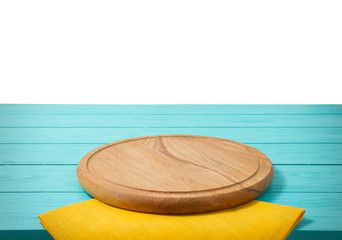 Round wood pizza cutting board and tablecloth on blue wooden table isolated on white background. Top view and copy space, Empty and template mockup with place for food. Selective focus