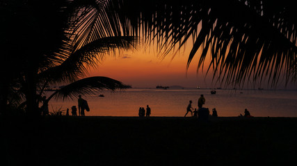 Silhouette of people on tropical beach at sunset - Tourists enjoying time