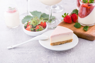 Delicious and nutritious handmade strawberry no bake frozen gradient colour fromage frais cheesecake slice with raw sarcocarp besides isolated with fair-faced gray background, copy space, close up