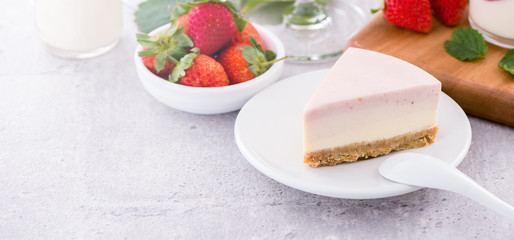 Delicious and nutritious handmade strawberry no bake frozen gradient colour fromage frais cheesecake slice with raw sarcocarp besides isolated with fair-faced gray background, copy space, close up