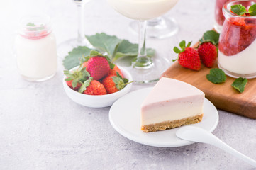 Delicious and nutritious handmade strawberry no bake frozen gradient colour fromage frais cheesecake slice with raw sarcocarp besides isolated with fair-faced gray background, copy space, close up