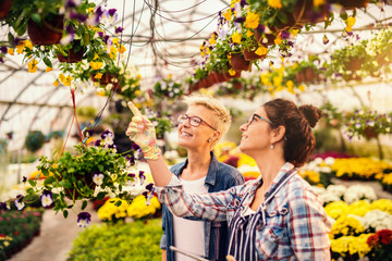 Florist helping customer to choose flowers. Greenhouse interior.