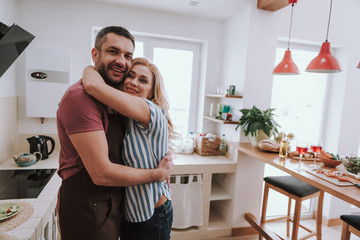 Beautiful blond lady embracing her husband in kitchen