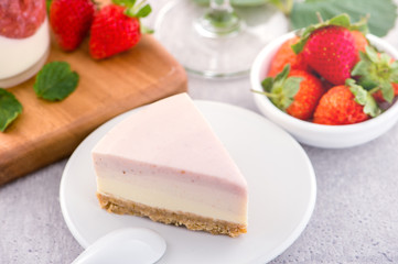 Delicious and nutritious handmade strawberry no bake frozen gradient colour fromage frais cheesecake slice with raw sarcocarp besides isolated with fair-faced gray background, copy space, close up