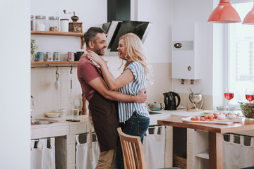 Happy loving couple hugging in kitchen at home