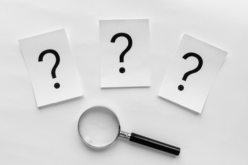 Three question marks with a magnifying glass