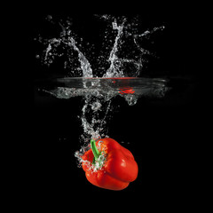 Red bell pepper falling in water with splash on black background, paprika, stop motion photography
