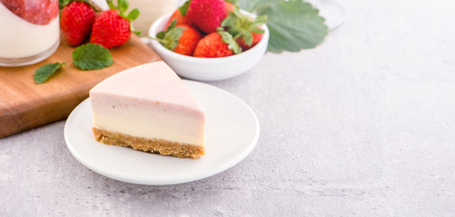 Delicious and nutritious handmade strawberry no bake frozen gradient colour fromage frais cheesecake slice with raw sarcocarp besides isolated with fair-faced gray background, copy space, close up