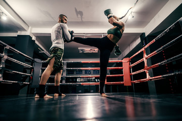 Powerful caucasian boxer girl in sportswear, with bandage on feet and boxing gloves on hands...