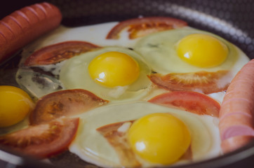 fried eggs with sausage and tomatoes