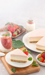 Delicious and nutritious handmade strawberry no bake frozen gradient colour fromage frais cheesecake slice with raw sarcocarp besides isolated with fair-faced gray background, copy space, close up