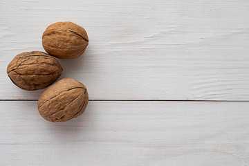 Walnuts on white wooden background.