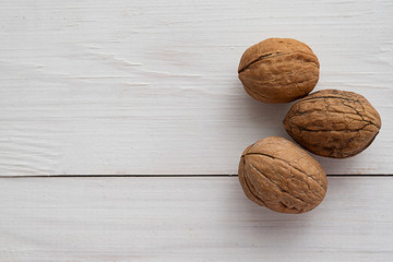 Walnuts on white wooden background.