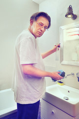 Older poor man cleaning his home with cleaner and sponge