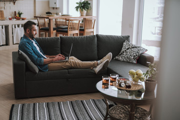 Obraz premium Handsome bearded man using modern laptop at home