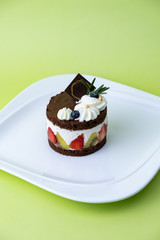 Chocolate cake with whip cream and fruit. Set on green background..