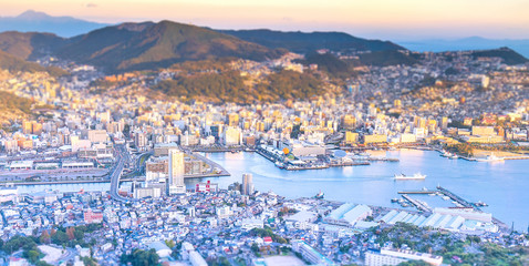 Business concept, tilt shift effect modern cityscape of nagasaki dusk from mount inasa, the new top 3 nightview of the world, aerial view, copy space