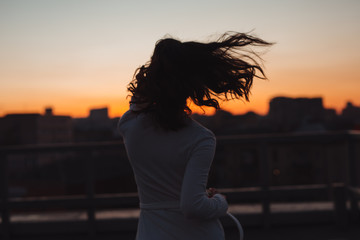 Silhouette of woman run into sunset in city