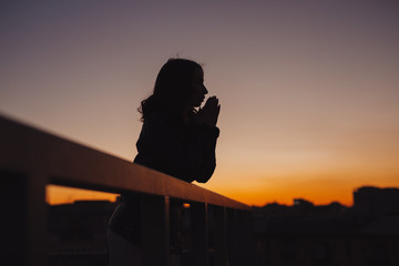 Silhouette of woman thinking about future at sunset in city