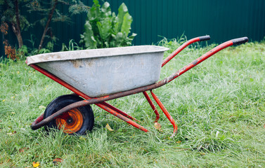 Obraz na płótnie Canvas Wheelbarrow on green grass lawn in a farm garden