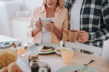 Close up of man and woman with cups standing next to the table