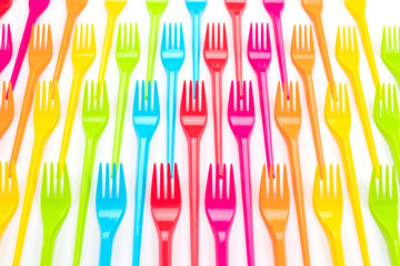 Many color plastic forks on a bright background