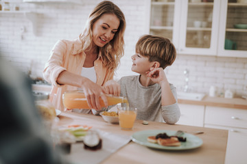 Boy looking at his mother pouring juice into his glass