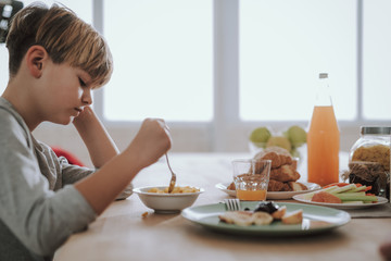 Boy looking at the bowl of cornflakes in front of him