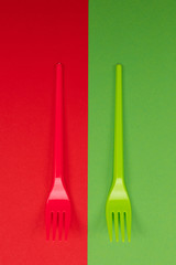 Pair of plastic forks in red and green atop of background