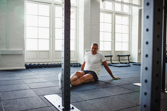 Smiling senior man sitting on the floor of a gym